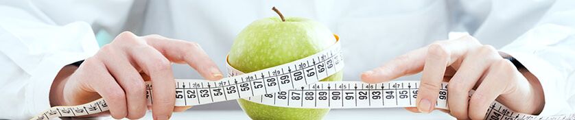 Das Mädchen misst den Apfel mit einem Zentimeterband